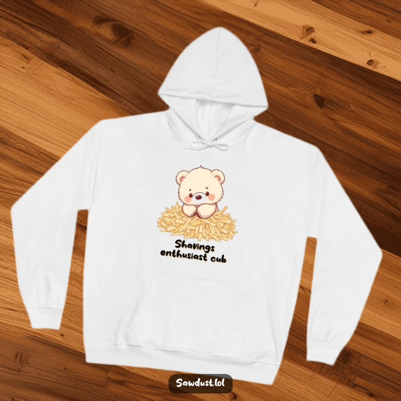 Funny hoodie featuring an adorable fluffy bear cub playing contentedly in a heap of wood shavings, radiating warmth.